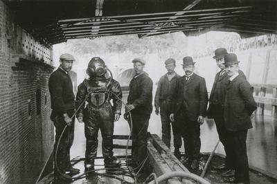863302 Afbeelding van een groep mannen bestaande uit enige werklieden, een duiker en drie 'hoge heren' op een vlonder ...